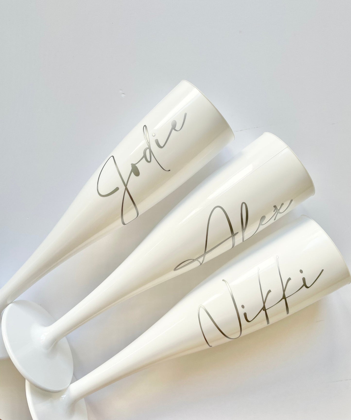 White personalised plastic champagne flutes for weddings, hen weekends or virtual hen do. Bride to be named glasses bridesmaids bride tribe